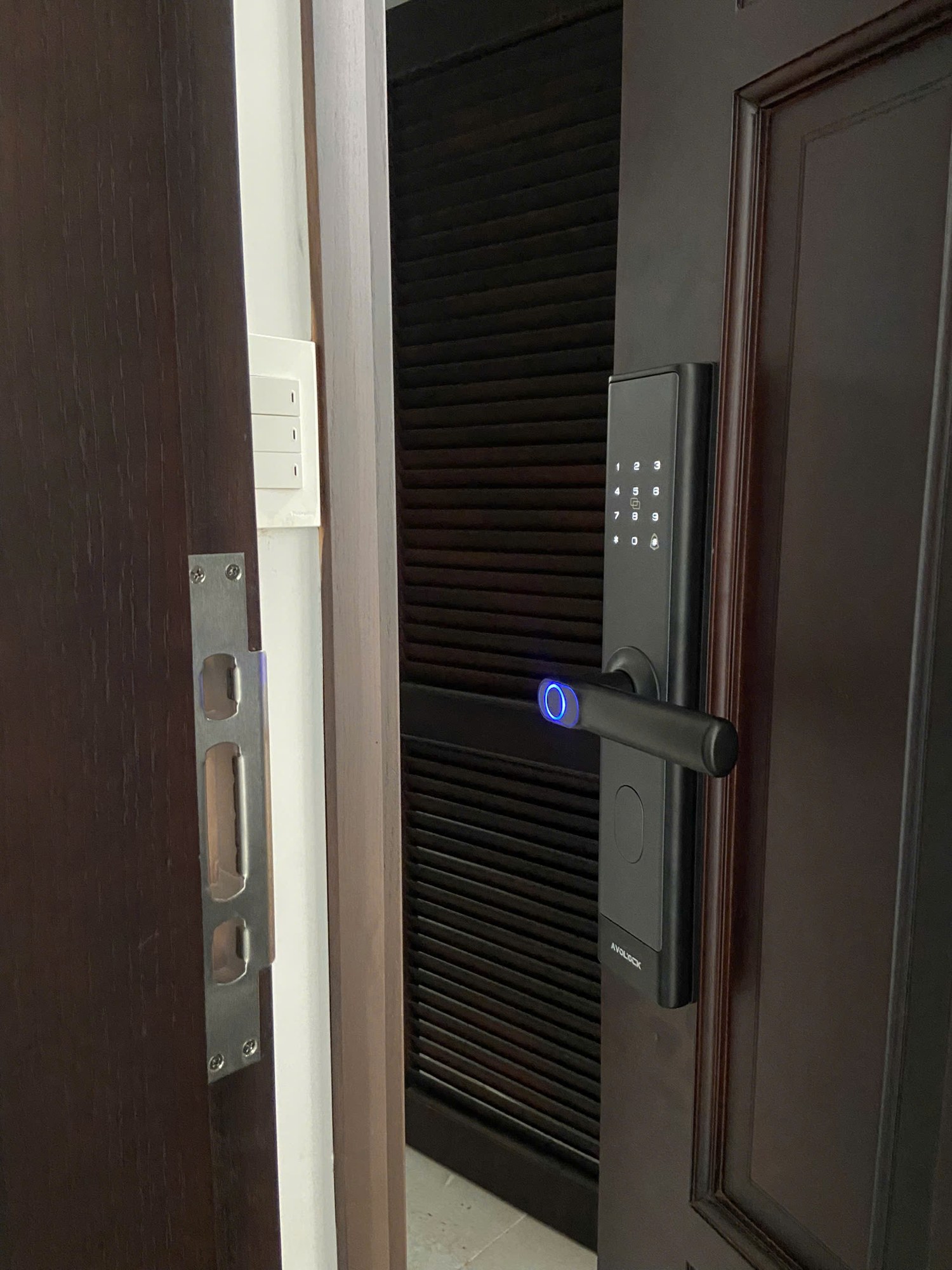 Khóa vân tay Avolock AV-67 — góc mặt ngoài và hông cửa, chốt khóa inox ăn khớp gọn gàng